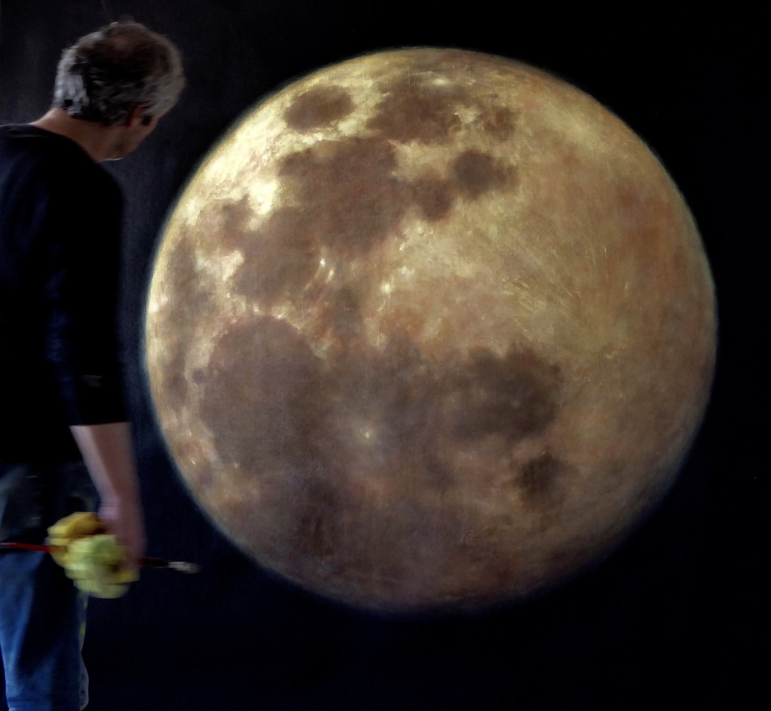 Jorge Estévez en su taller junto a una gran pintura de luna